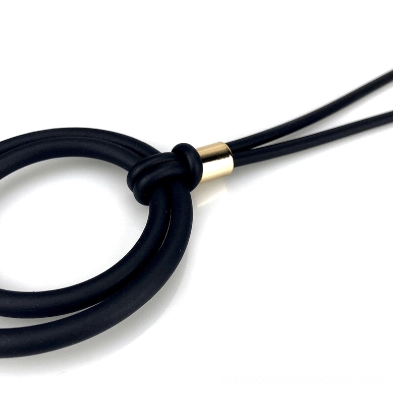 Super close-up of black gothic necklace highlighting knotted gold metal accent on matte black rubber cord