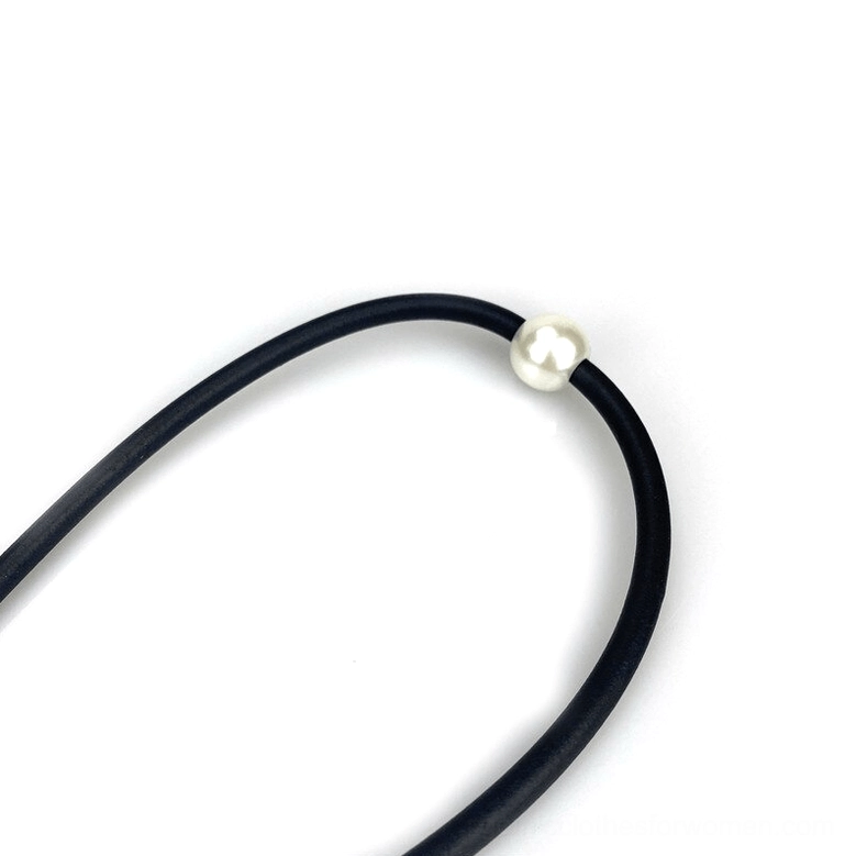 Minimalist black rubber cord necklace with single white faux pearl pendant flat lay view