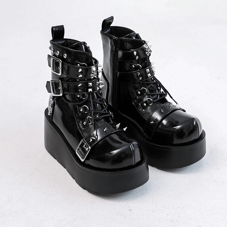 Pair of black gothic platform ankle boots with lace-up buckles and rivets flat lay