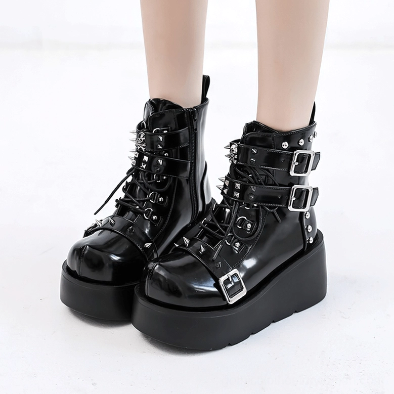 Black gothic spiked platform ankle boots on model showing thick sole and patent finish