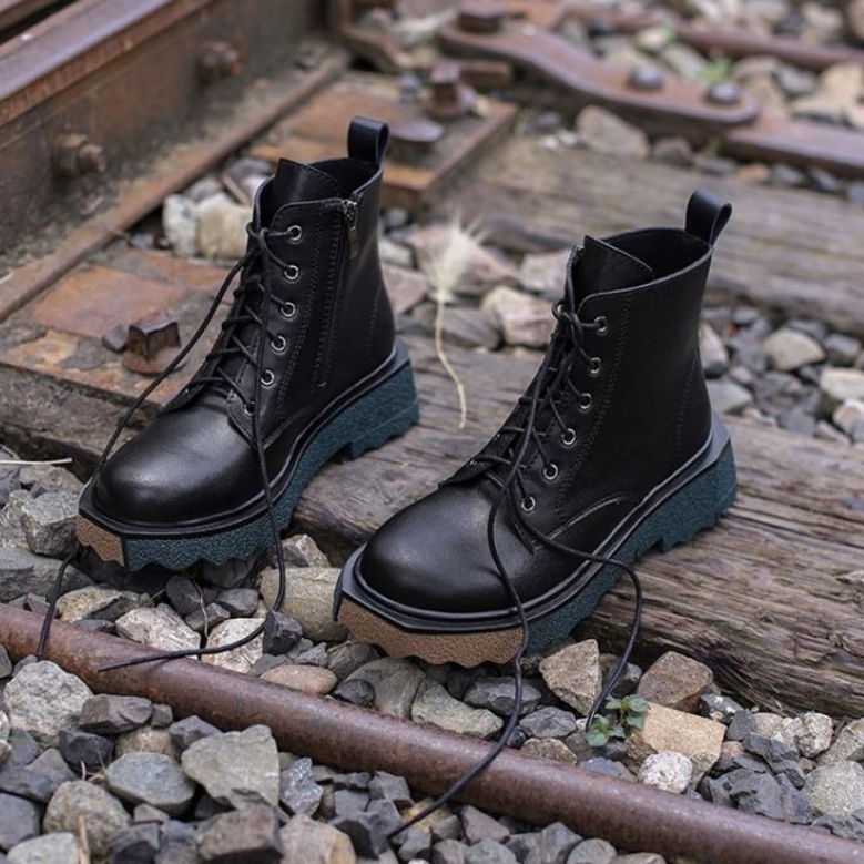 Black leather gothic platform boots styled outdoors on railway tracks, authentic wear demonstration, industrial aesthetic background