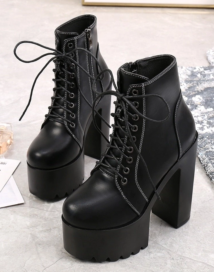 Black gothic platform boots with side zipper and chunky block heel, marble tabletop lifestyle shot