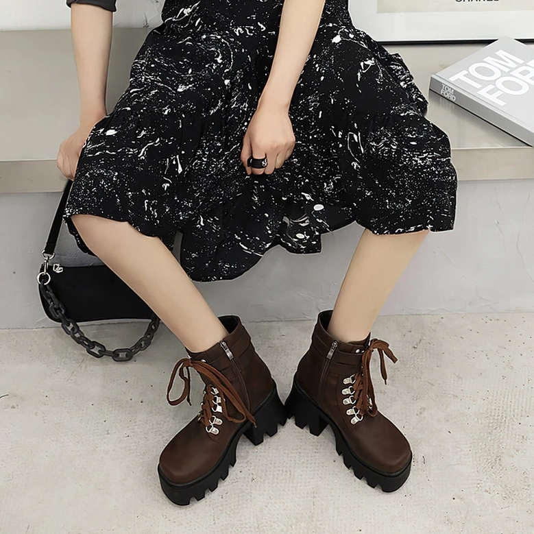 Black gothic platform boots showing decorative stitching and architectural heel design, detail-focused styling photograph