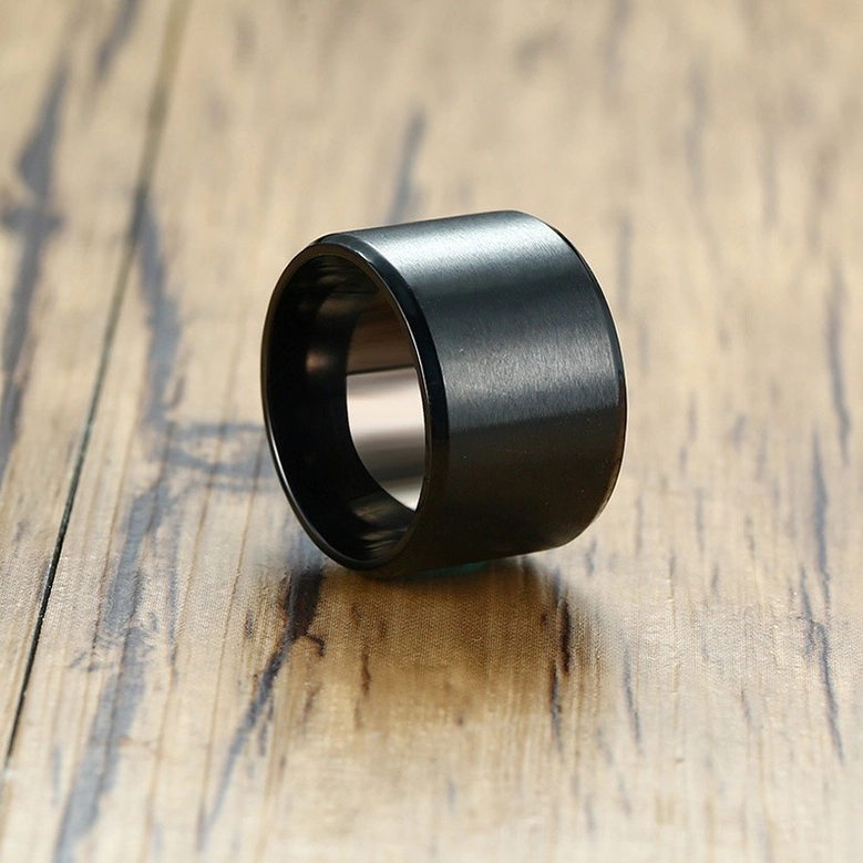 Side 3/4 angle of black stainless steel gothic ring displaying brushed matte surface and smooth inner band on wood background