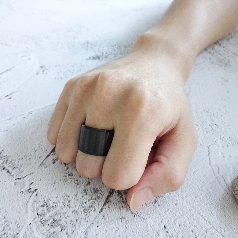 Black gothic ring worn on human index finger, close-up hand shot on textured concrete background showing fit and real-world wearability