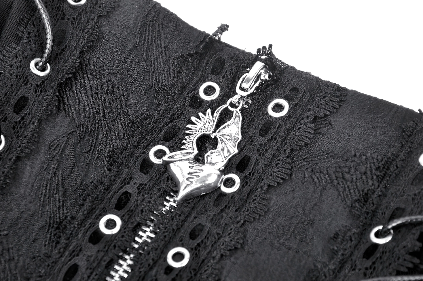 Macro close-up of black gothic skirt cross zipper pendant with silver metal finish and lace eyelet fabric background