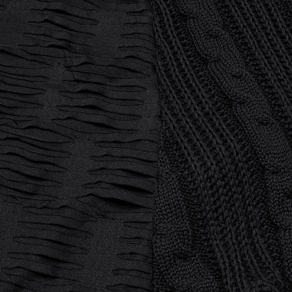 Close-up detail of black gothic knit fabric showing torn distressed cable knit weave and texture