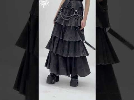 Side profile of black gothic layered skirt highlighting chain straps and raw frayed tier hems with partial model view