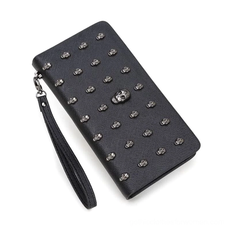 Black gothic skull studded long wallet with silver rivets and central skull decoration, shown from left oblique angle with detachable wrist strap