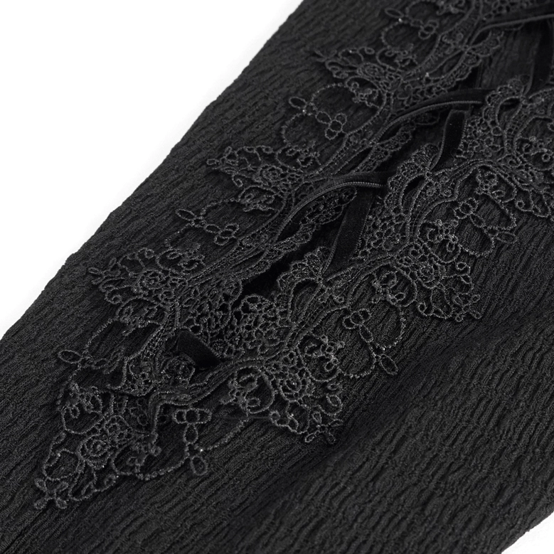 Fabric close-up of black gothic flared trousers showing textured crinkled material and embroidered lace