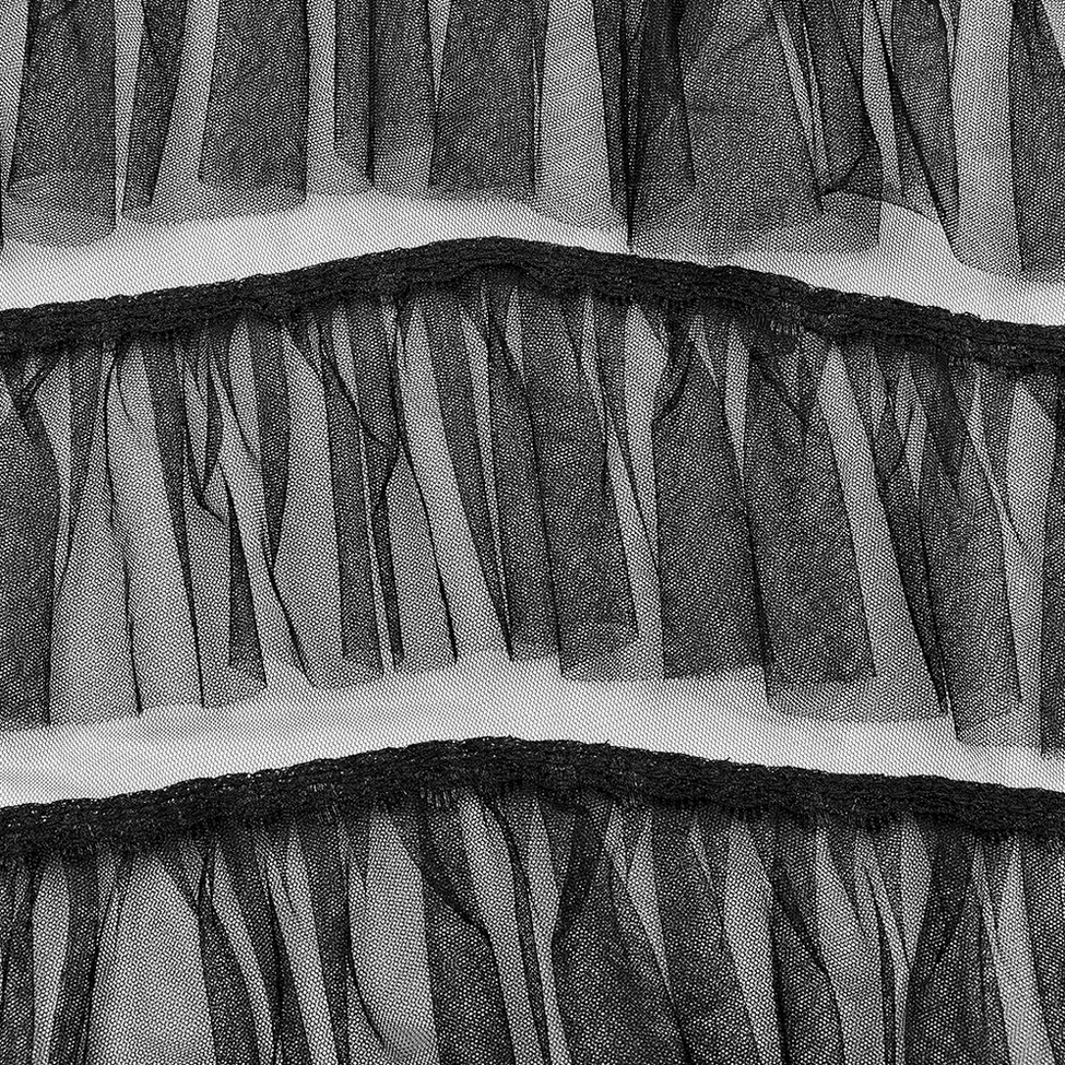 Macro close-up of black sheer tulle ruffle texture showing layered mesh edges and fabric quality