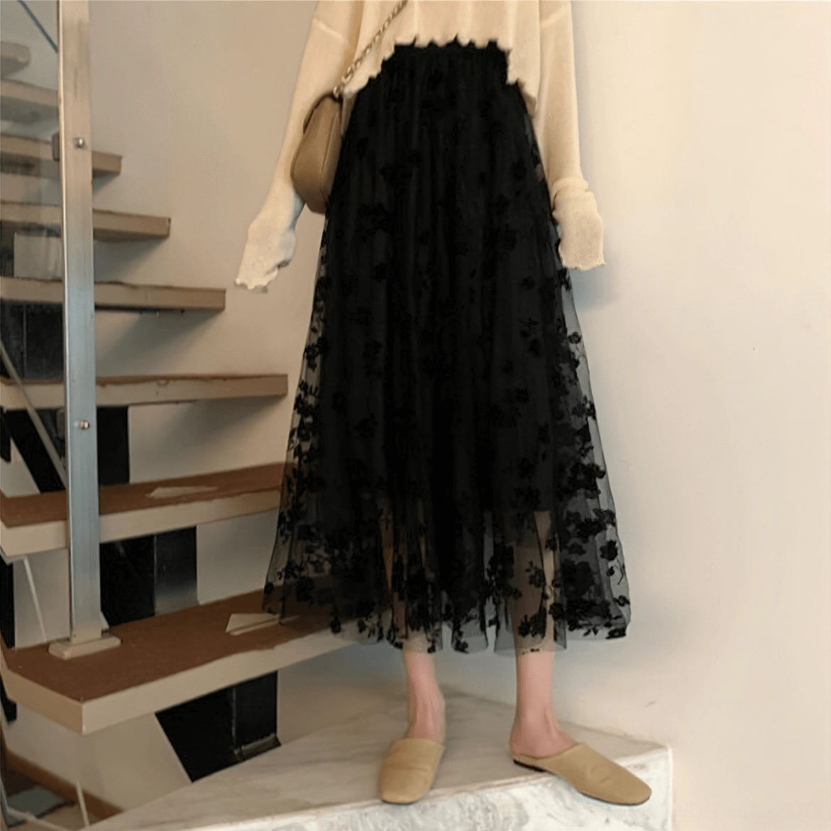 Solid black gothic tulle midi skirt worn with beige knit top, staircase setting, elegant gothic silhouette