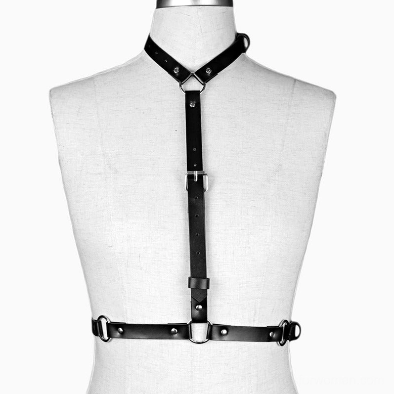 Black synthetic leather body harness with crossed neck strap and central vertical belt on mannequin, front view detail