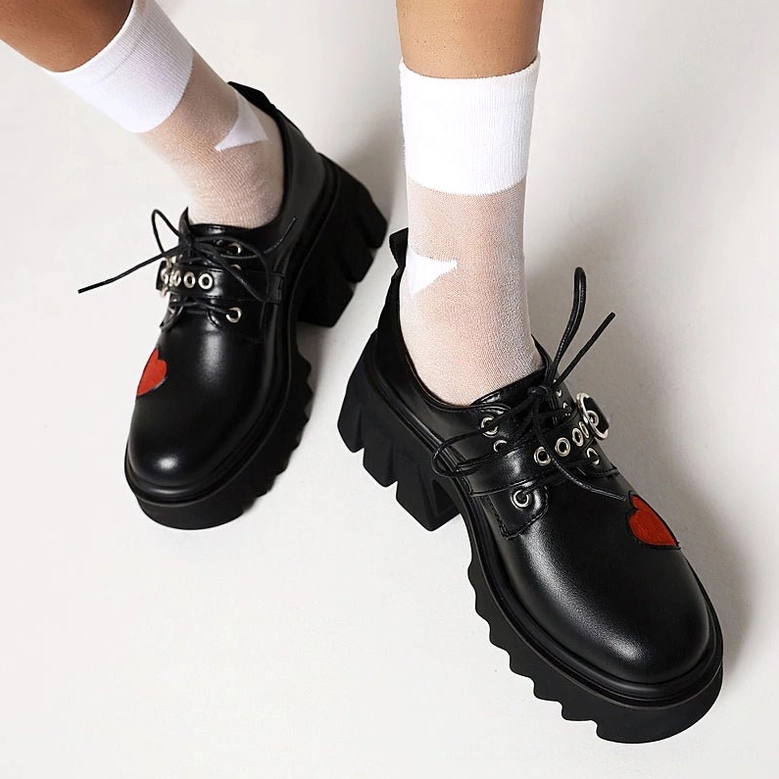 Black lace-up gothic platform pumps with red heart patches and thick rubber sole, flat side view