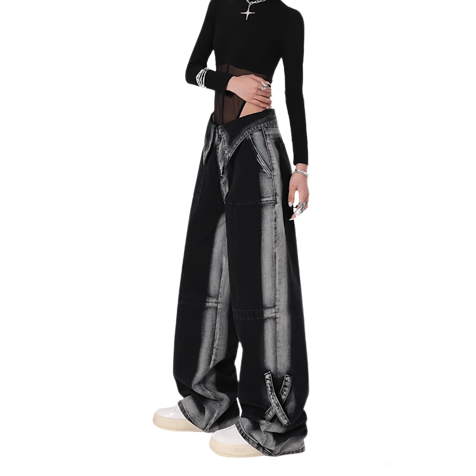 Side front view of high-waist black denim pants showing loose fit silhouette and hem strap accents