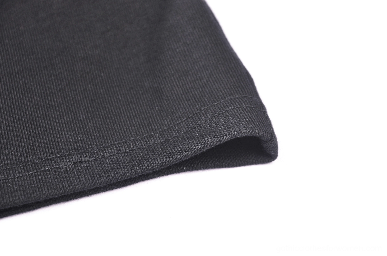 Close-up of black lace bodycon dress hem showing solid black fabric, smooth matte finish texture, and neatly folded stitching