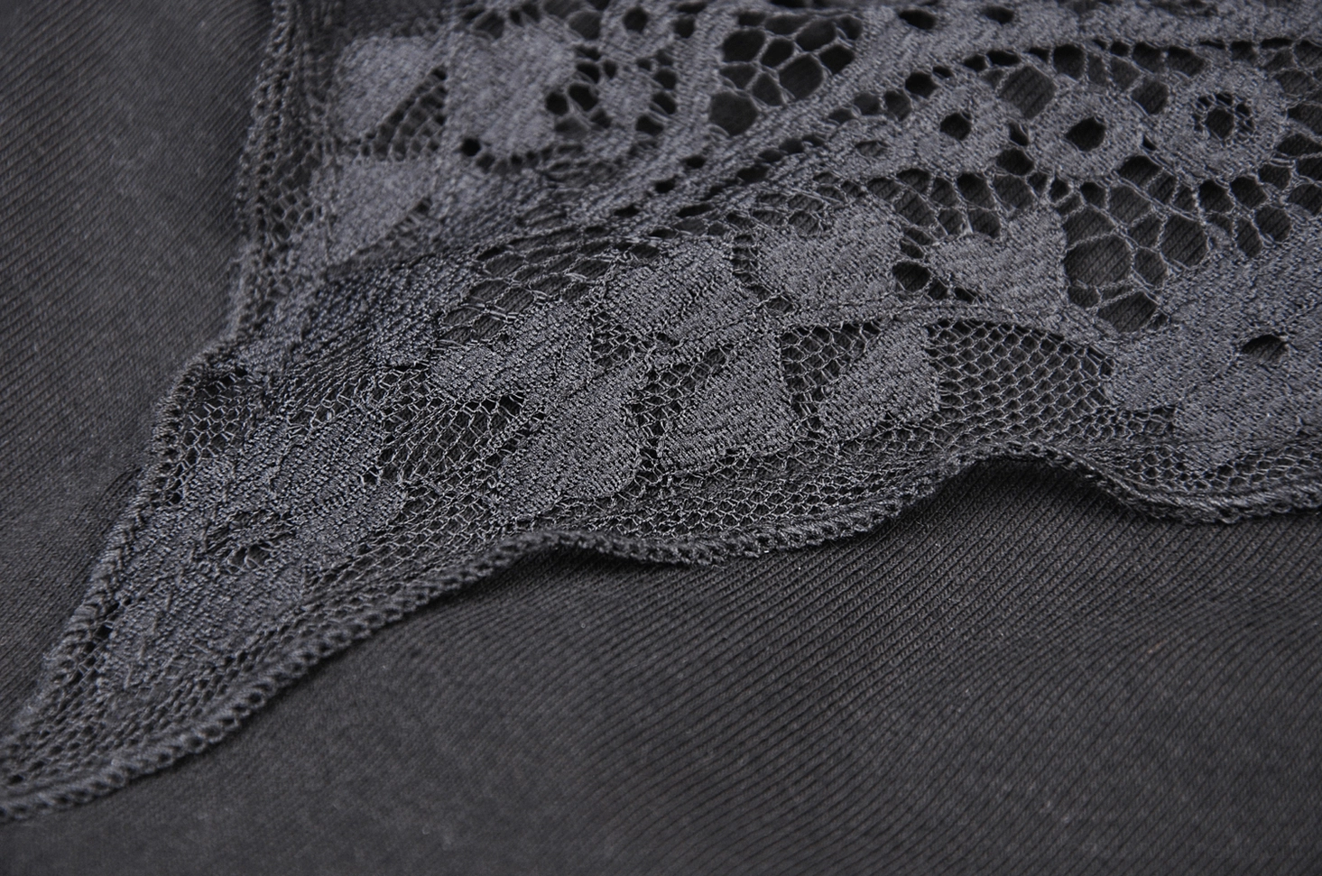 Close-up detail of intricate black floral lace and fabric junction, showing quality of lace craftsmanship and delicate pattern work