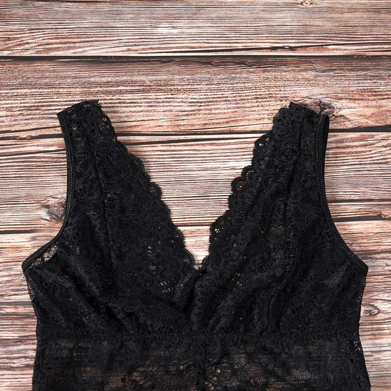 Black lace jumpsuit flat lay top-down view on wooden surface, showing deep V-neck sleeveless lace top design
