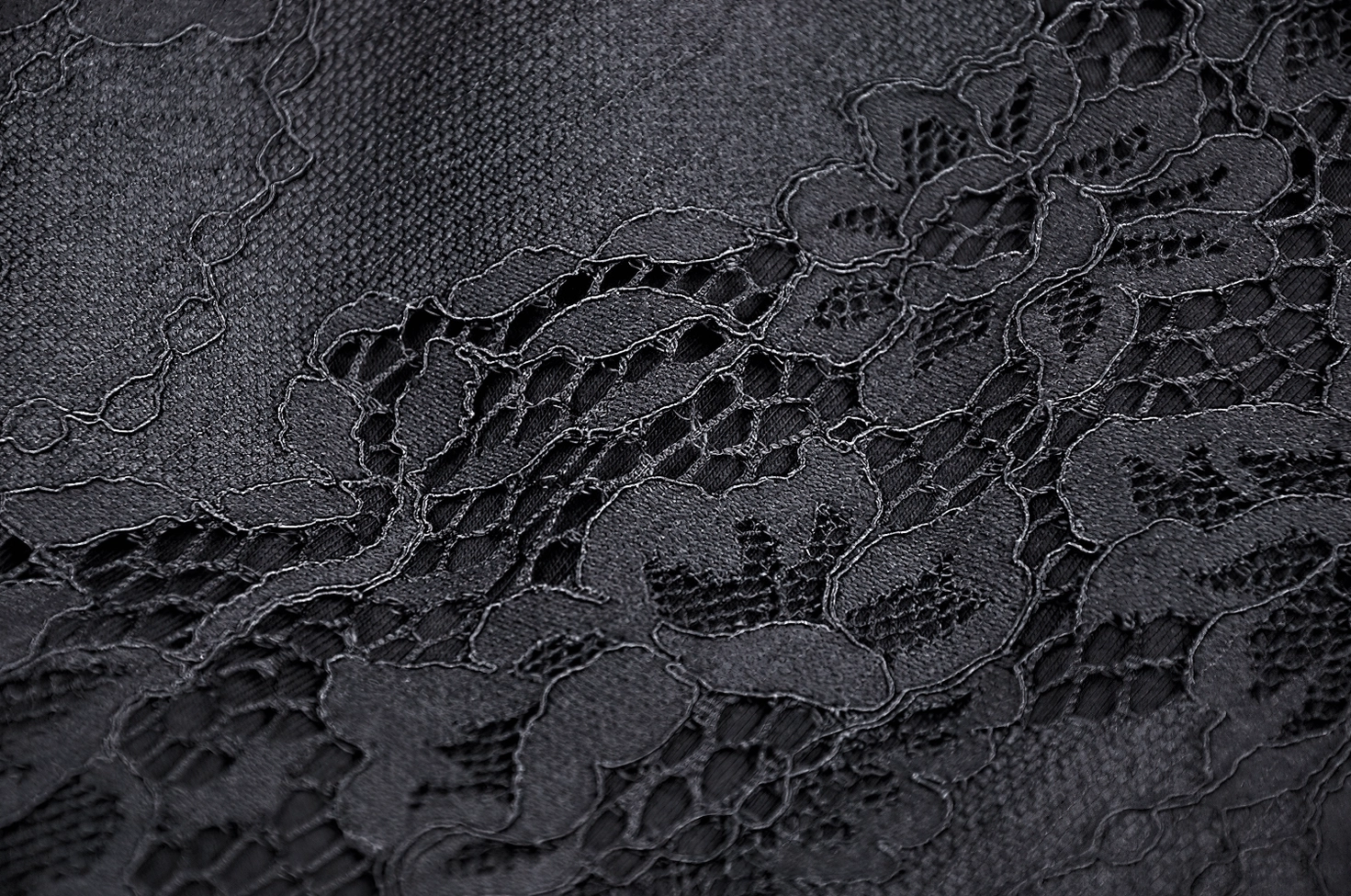 Intricate floral lace fabric texture close-up showing gothic pattern details of black mermaid skirt material