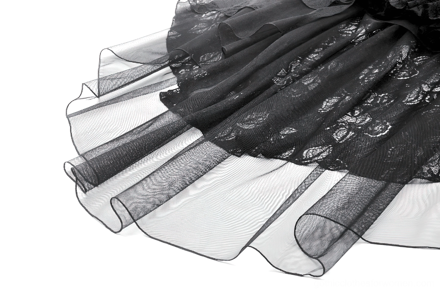Close-up of black high-low skirt hem showing sheer tulle overlay and patterned lace edges
