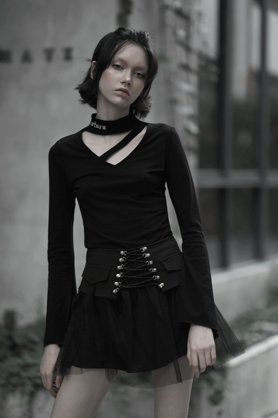 Black lace-up gothic mini skirt on model outdoors urban setting with long-sleeve top and choker styling