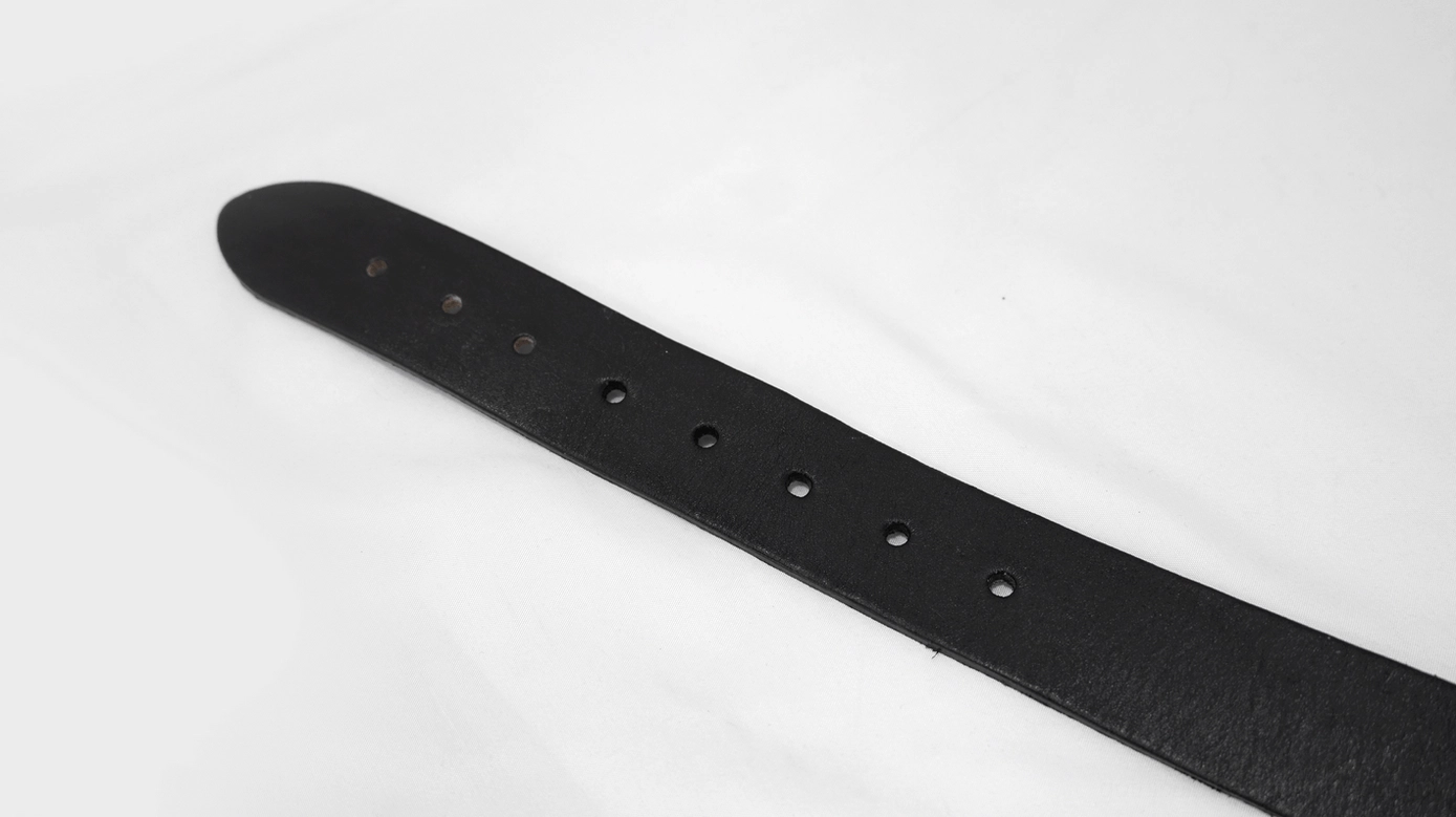 Overhead flat lay of genuine matte black leather belt strap showing pre-punched size adjustment holes for customization