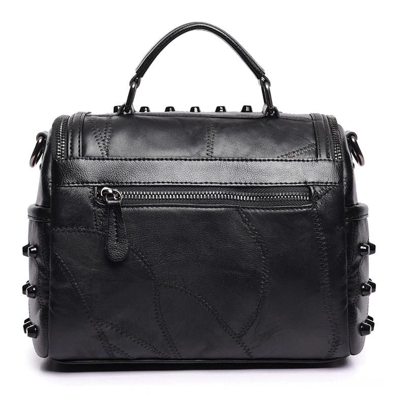 Rear view of black gothic leather crossbody bag featuring exterior zipper pocket and patchwork leather texture with all-over rivet embellishment