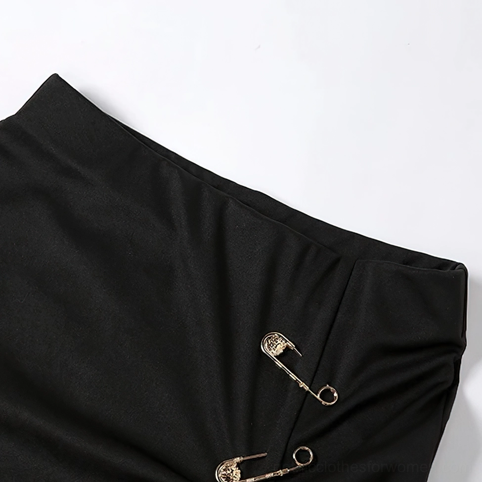 Close-up flat lay of black midi skirt fabric showing smooth broadcloth texture and metal safety pin embellishments detail