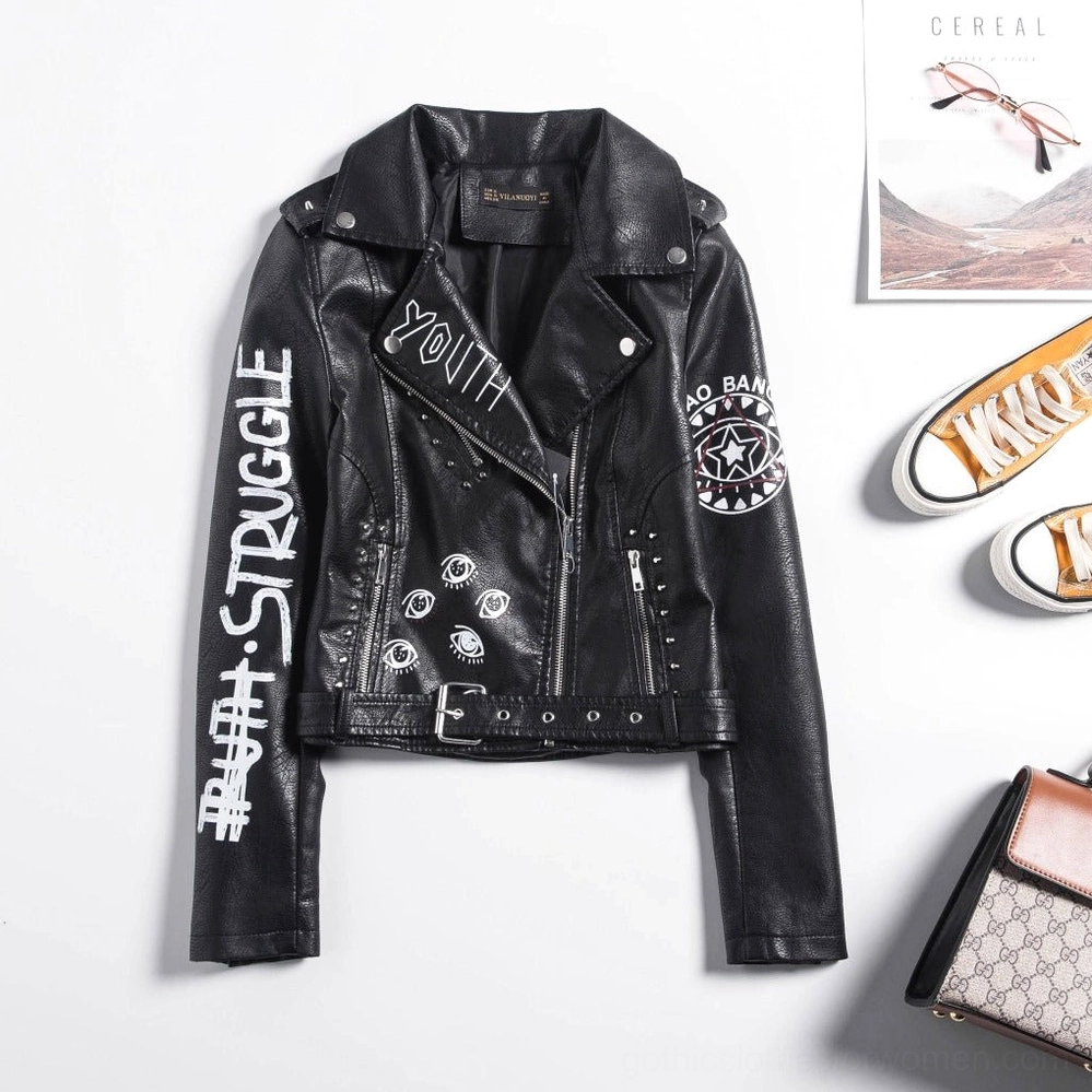 Front flat lay of black PU leather jacket displaying full printed motifs studs and zipper details with daily accessories