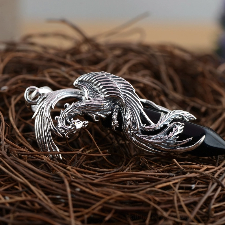 Phoenix stone pendant top oblique view showing detailed silver carving over black bullet-shaped obsidian on nest background