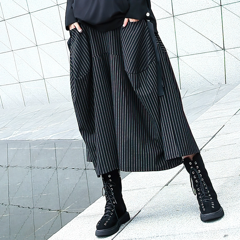 Three-quarter side view of black pinstripe gothic skirt showing side strap detail and oversized pocket construction