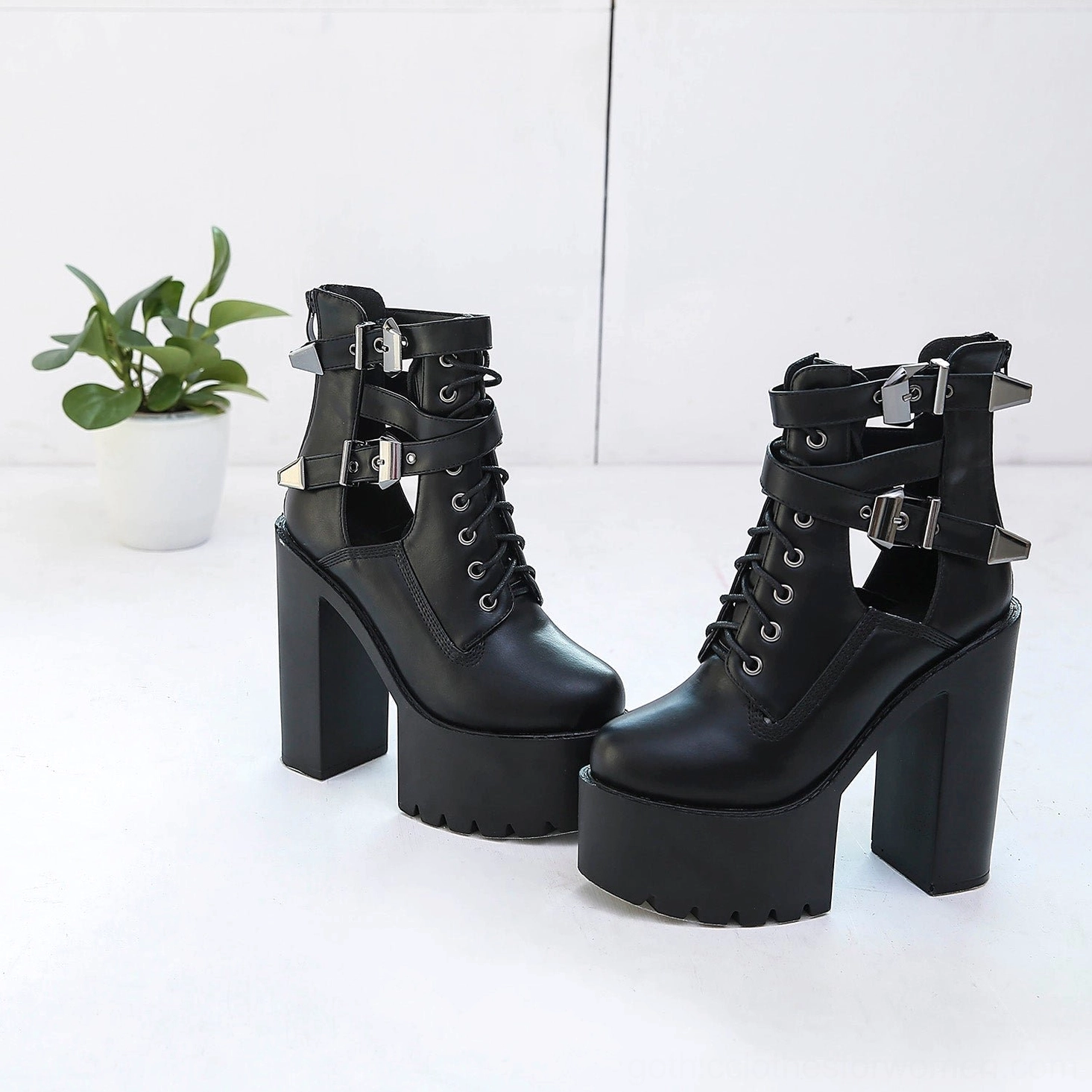 Black gothic platform lace-up ankle boots with multiple metal buckle straps and thick platform sole, styled with alternative aesthetic backdrop