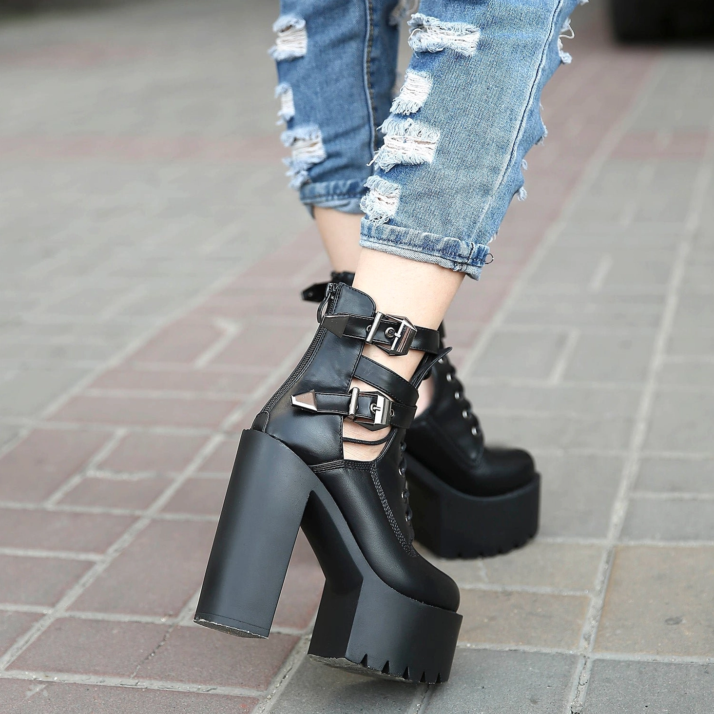 Black platform lace-up boots showcasing round toe silhouette, architectural cutouts, metal buckle straps, and commanding heel construction for goth fashion