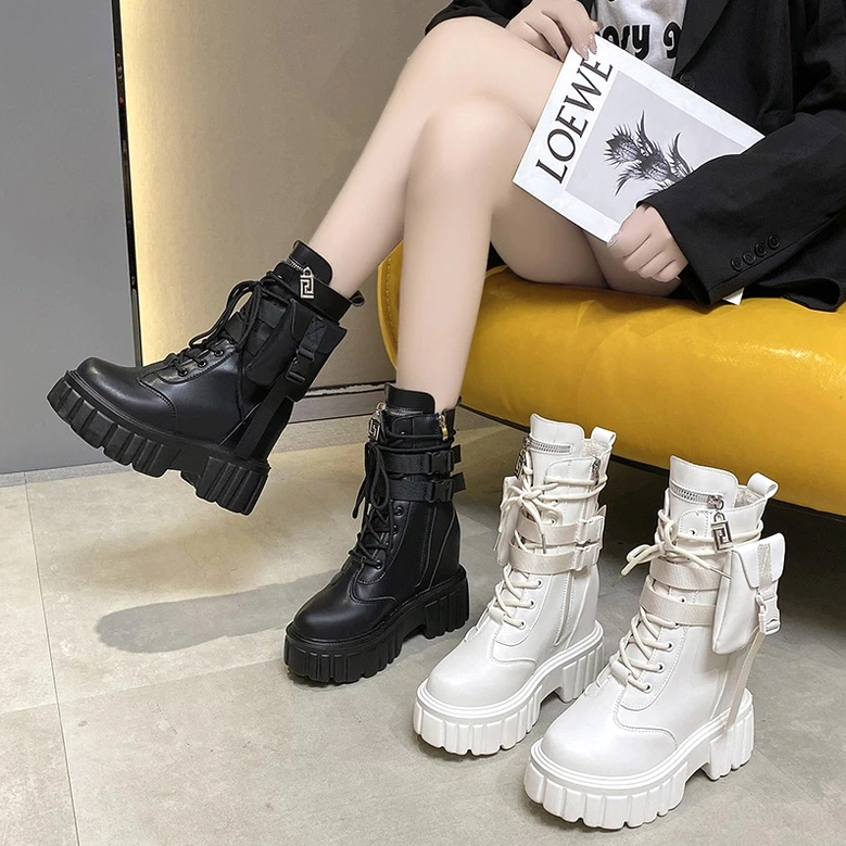 Seated model wearing black and white platform combat boots while holding magazine on yellow sofa
