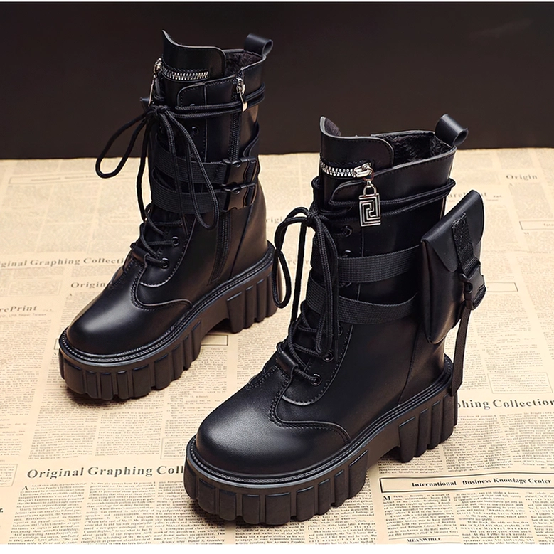 Pair of black platform combat boots with lace-up closure, side pocket, and decorative strap details on newspaper