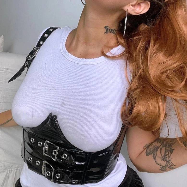 Side close-up detail of black PU leather gothic crop top with silver buckle fasteners on female model with red hair