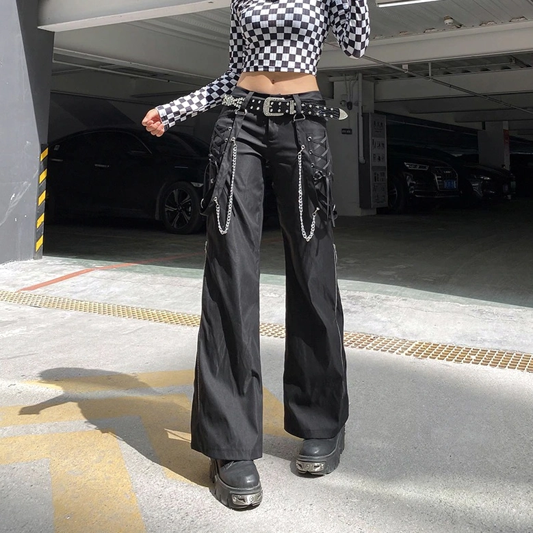 Black punk-inspired cargo trousers with lace-up side pockets and metal chain accents, lifestyle fashion photography