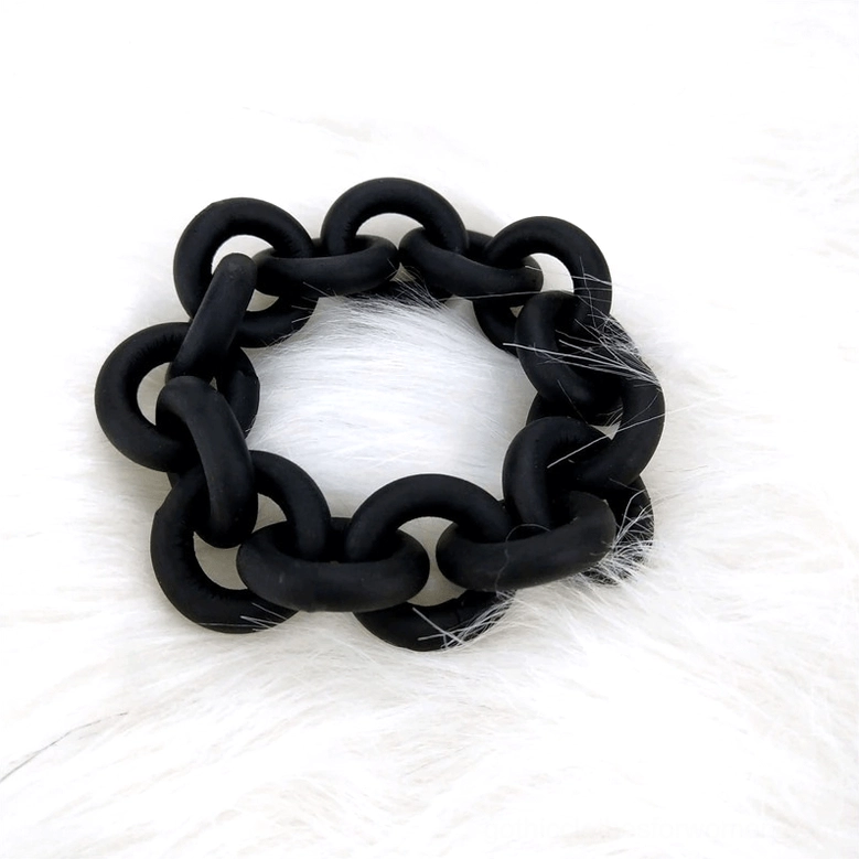 Chunky black matte rubber linked chain gothic bangle on white faux fur background, top-down product shot