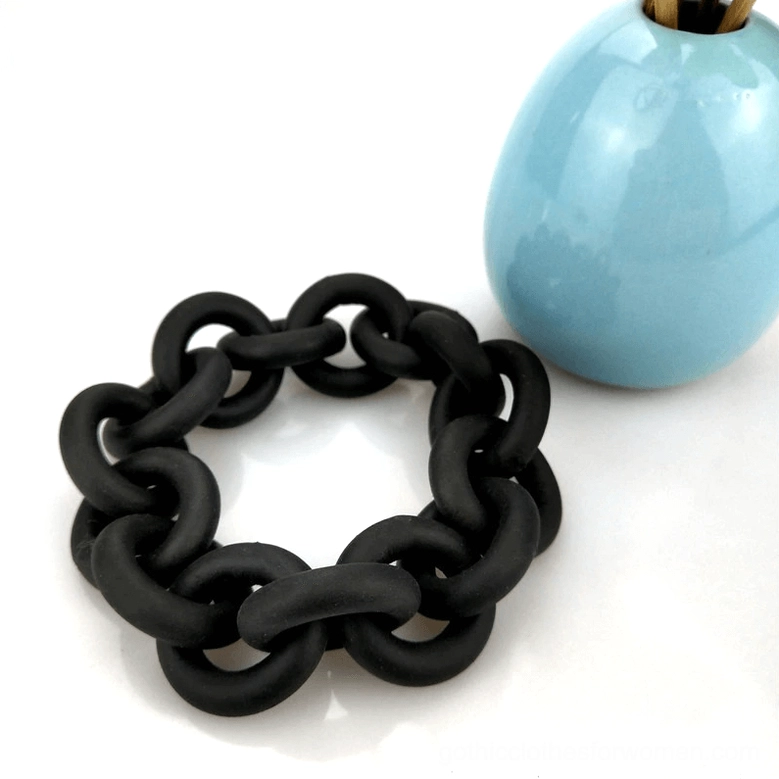 Handcrafted black rubber chain bangle on white background with blue ceramic home decor, flat lay styling