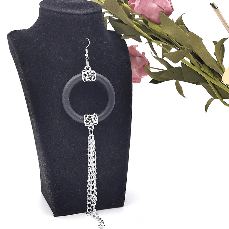 Single black rubber hoop drop earring with silver chain tassel, front view on mannequin with pink flowers, alternative jewelry styling