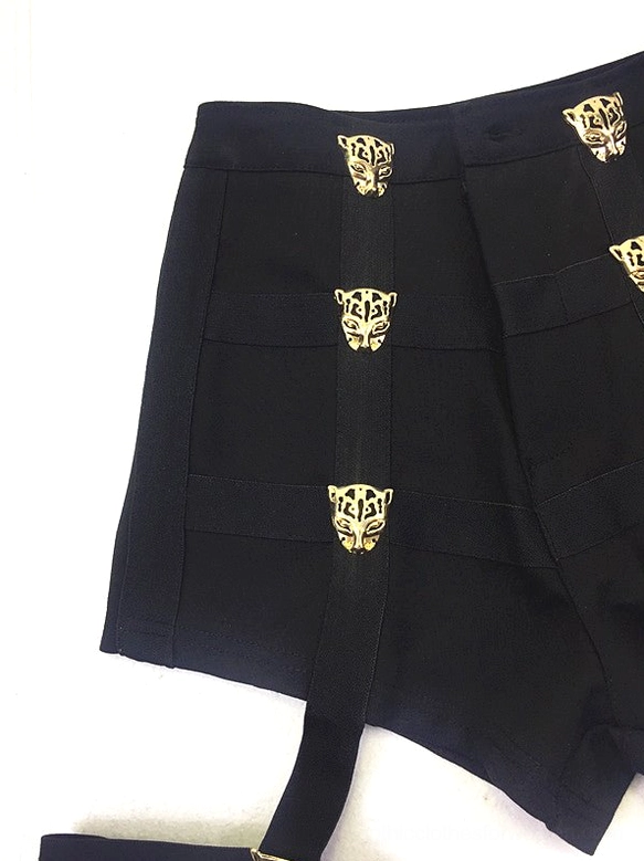 Alternative styling flat lay of black high-waist shorts with vertically arranged decorative metal buttons