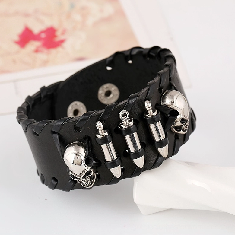 Skull and bullet punk leather bracelet with silver metal accents on white display prop, side oblique angle showing braided leather texture and snap fasteners