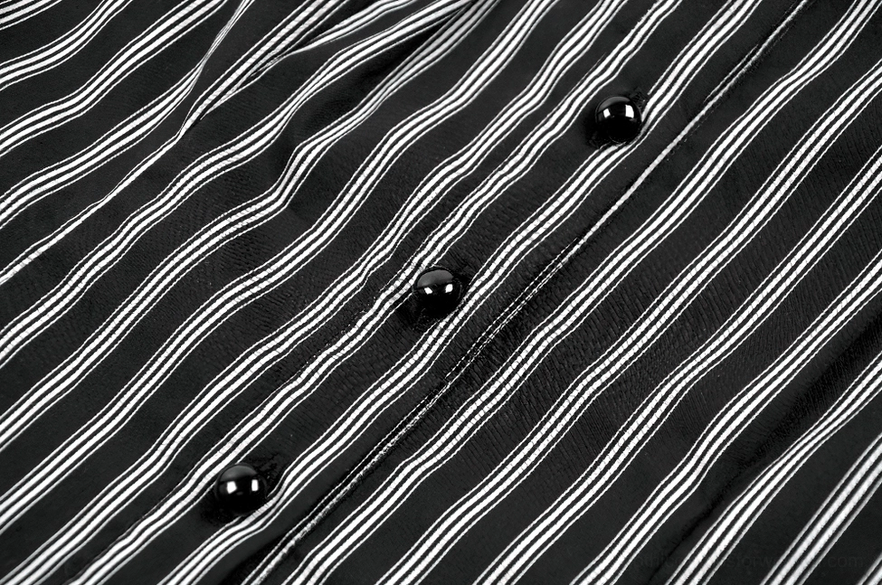 Macro close-up of black round button and tightly woven black-white striped fabric texture