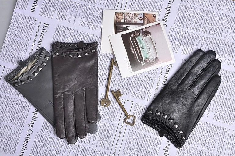 Black studded leather women's gloves with gothic rivets worn in car, lifestyle wearing shot