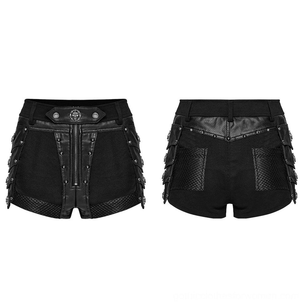 Flat lay front view of black studded gothic shorts showing skull belt buckle, front zipper, leather panels, and detailed hardware against white background