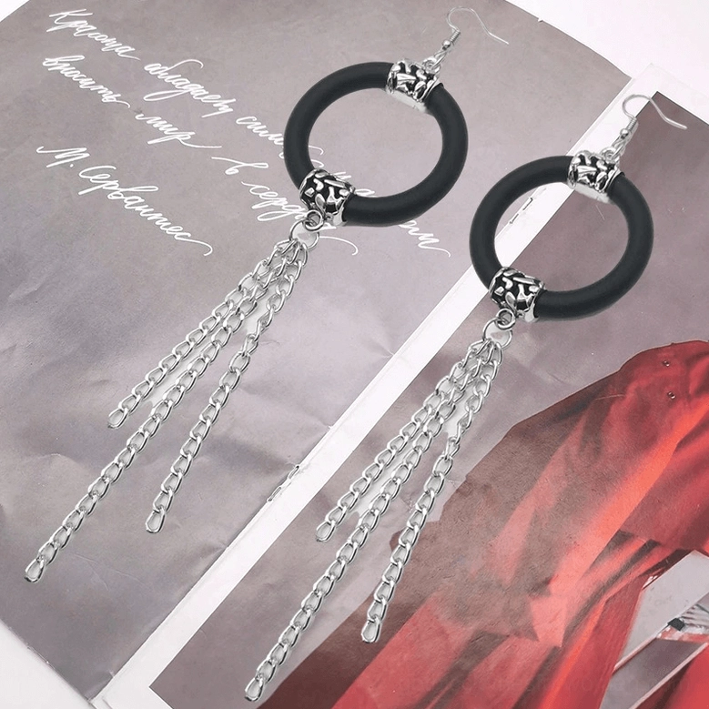 Pair of long black drop earrings with vintage silver chain tassels on magazine background, lifestyle gothic jewelry display