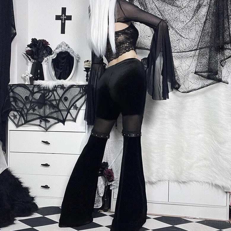 Back full view of black velvet flare pants with mesh thigh panels and studded leather accents on model
