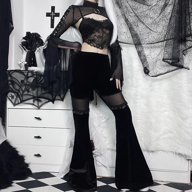 Three-quarter front view of black velvet flare pants on model showing mesh thigh panels and studded trim details