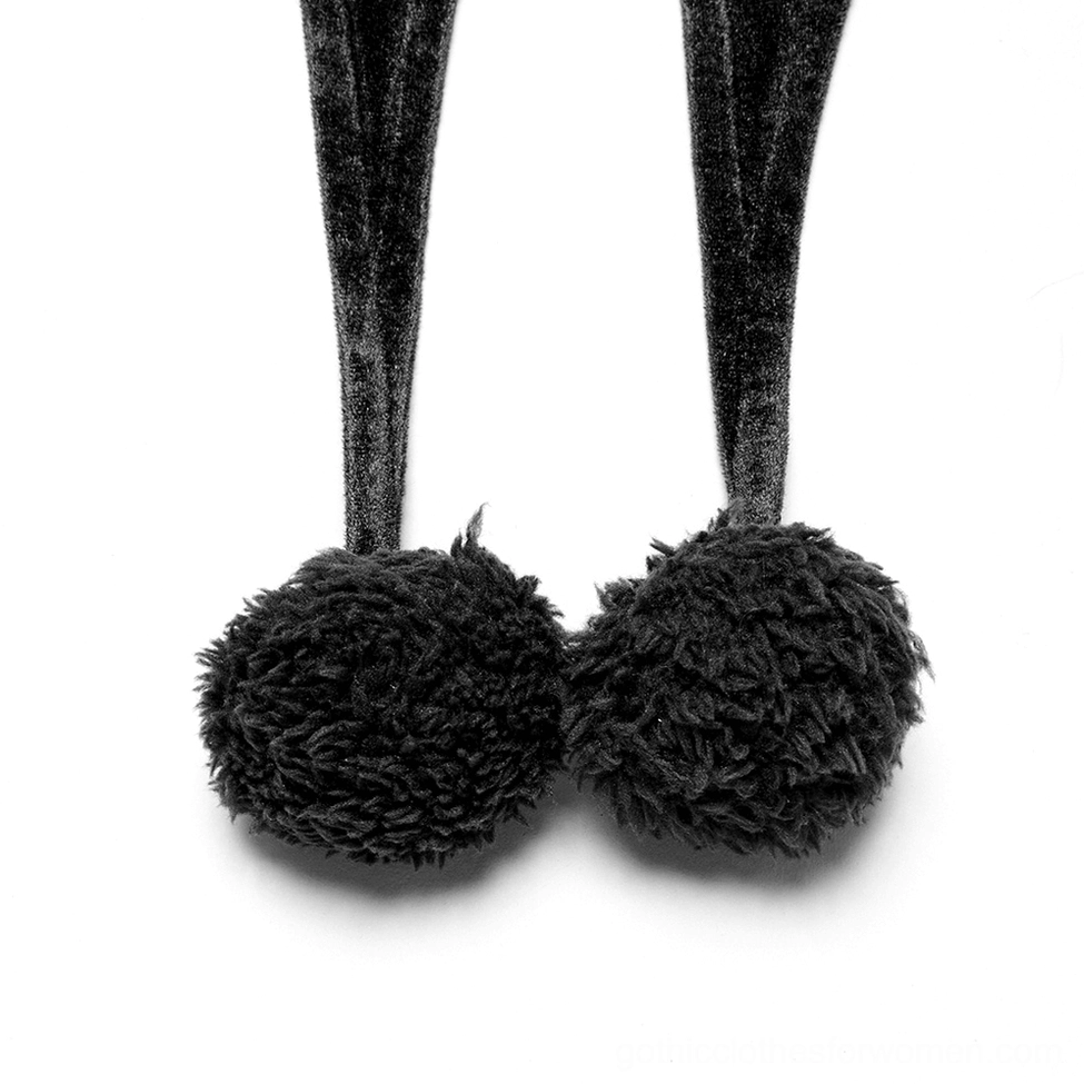 Close-up flat lay detail of black velvet gothic cape pom-pom tail showing fluffy fuzzy embellishments and velvet straps