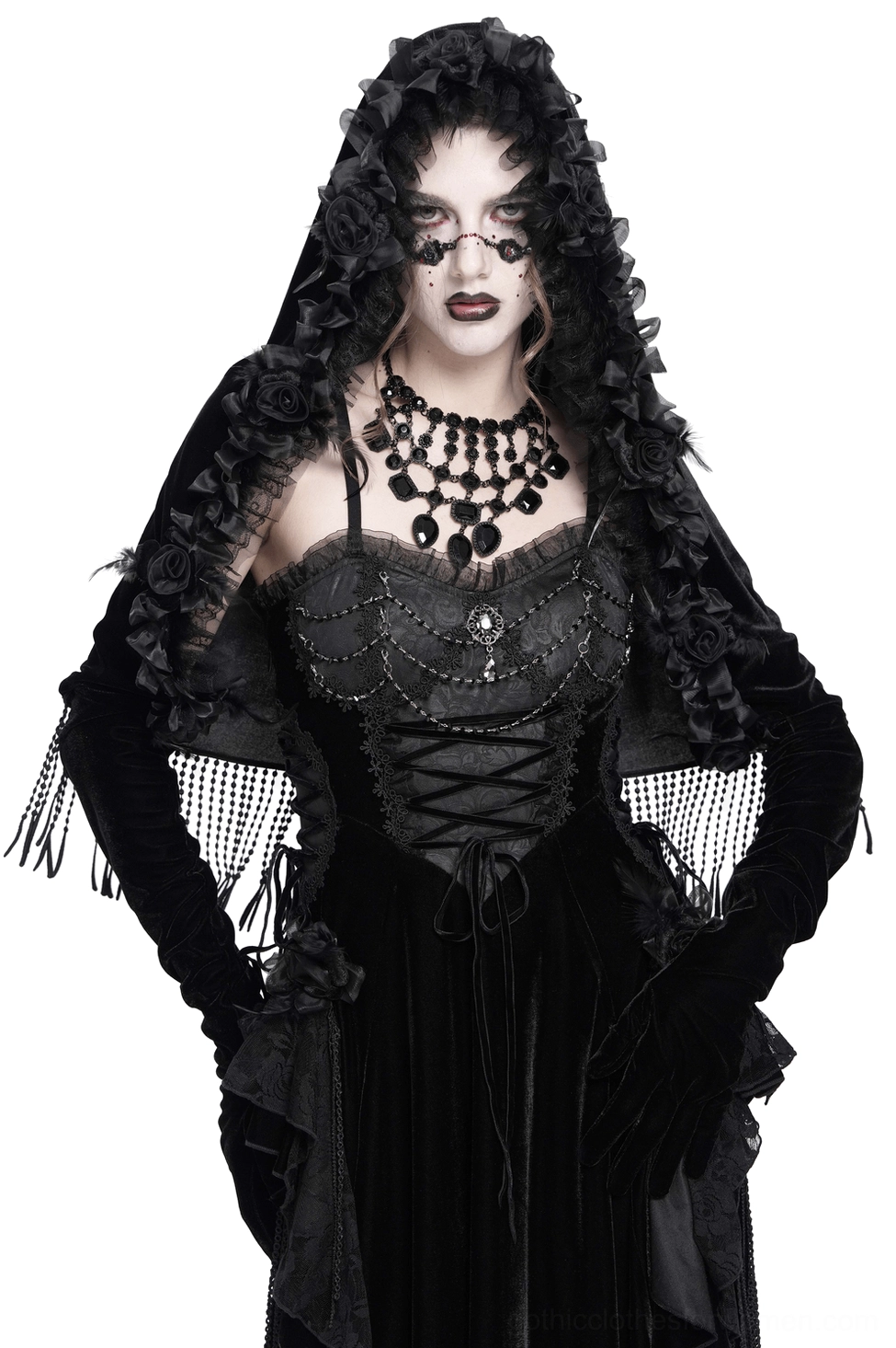 Black velvet hooded cape with rose floral trim worn by gothic model, front three-quarter view showing beaded fringe hem and ruffled hood details